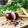 Red onion, parsnip and herbs on a wooden cutting board (illustrative photo)