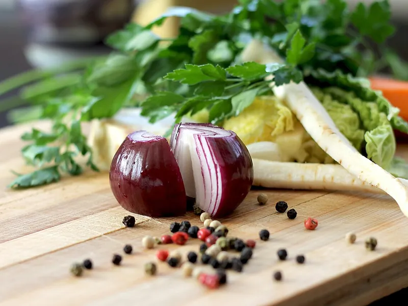 Red onion, parsnip and herbs on a wooden cutting board (illustrative photo)